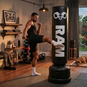 RAM O2 Bokspaal / Staande Bokszak - Zwart Man geeft een trap tegen een zwarte RAM O2 XL bokspaal in een thuisgym