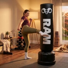 RAM O2 Bokspaal / Staande Bokszak - Zwart Jonge vrouw geeft een hoge trap tegen de RAM O2 vrijstaande bokspaal in haar thuisgym
